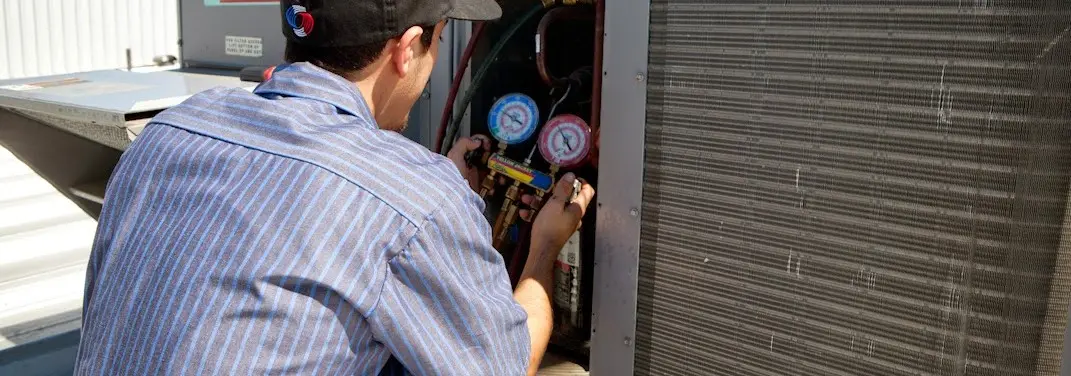 HVAC technician servicing a condenser unit in Bloomington